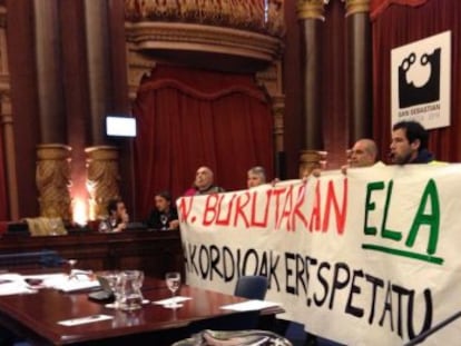 Trabajadores del Ayuntamiento de San Sebastián despliegan una pancarta contra la supresión de la paga extra durante el pleno municipal.