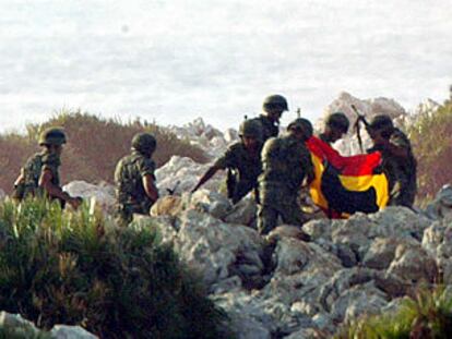 Un grupo legionarios recoge una bandera española antes de abandonar Perejil.