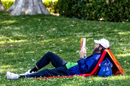 Un hombre lee, tumbado en El Retiro, durante la inauguración de la Feria del Libro.