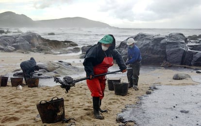 Trabajadores recogen el petróleo derramado del Prestige que cubre la playa de Muxia, en esta imagen tomada el 23 de noviembre de 2002.