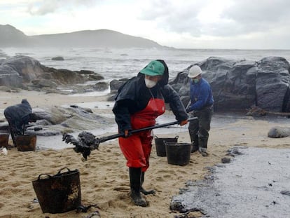 Trabajadores recogen el petróleo derramado del Prestige que cubre la playa de Muxia, en esta imagen tomada el 23 de noviembre de 2002.