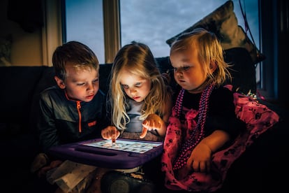 Tres niños miran absortos una pantalla.