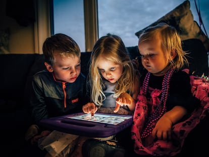 Tres niños miran absortos una pantalla.