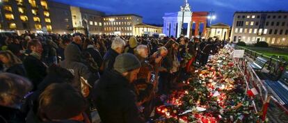 Una multitud deposita flores y velas en homenaje a las víctiams de lso atentados de París en la puerta de Brandenburgo en Berlín.