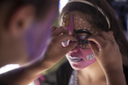 Una hombre acomoda unas pestañas postizas a una mujer. Se preparan para el desfile.