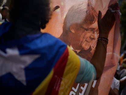 Un hombre sujeta una imagen del expresidente catalán Carles Puigdemont durante una protesta contra su detención frente al consulado italiano en Barcelona, este viernes.