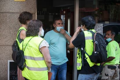 Un  equipo de informadores piden a un comerciante que guarde las medidas de seguridad.