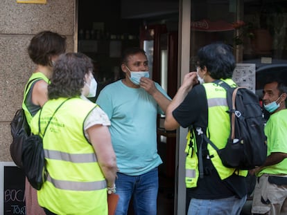 Un  equipo de informadores piden a un comerciante que guarde las medidas de seguridad.