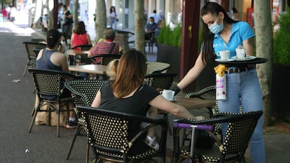 Una camarera sirve en una terraza de un bar de Sabadell.