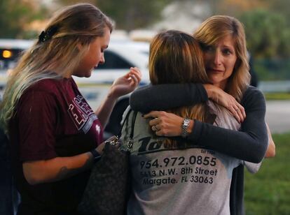 Una mujer abraza a dos chicas en el puesto policial habilitado en el parking del instintuto Stoneman de Florida tras el tiroteo.