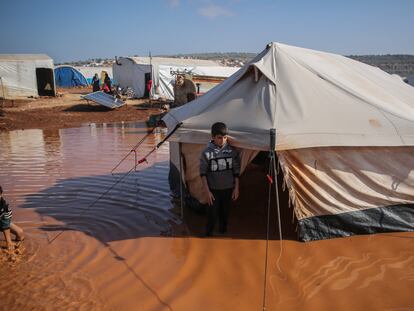 Dos niños sirios son fotografiados junto a su casa, una tienda de campaña, ahora inundada debido a las inundaciones a causa de las fuertes lluvias que cayeron sobre el campo de refugiados de Ma'arrat al-Nu'man, en Siria, el 17 de diciembre de 2020.