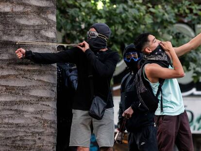 Un joven se hace un selfi mientras otro apunta un tirachinas durante una protesta en Santiago de Chile.