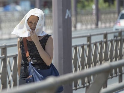 Una mujer se protege la cabeza del sol con un pañuelo.