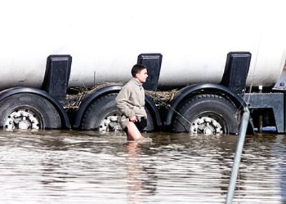 Un vecino de Santiponce (Sevilla) cruza una zona inundada por las lluvias de ayer.