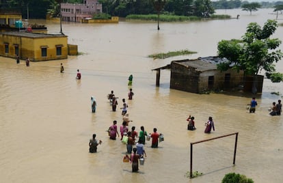 Residentes afectados por las inundaciones tratan de recoger utensilios en Udaynarayanpur, India.