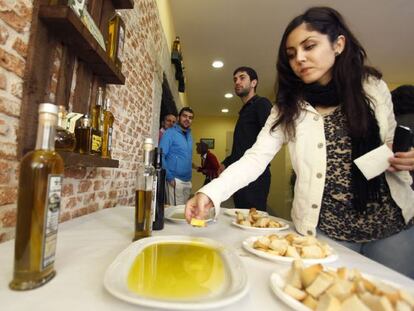 Una mujer prueba aceite de oliva con pan durante su visita a la primera Oleoteca Internacional dedicada al aceite de oliva virgen, en Santa Cruz del Valle (Ávila)