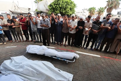 Ciudadanos palestinos rezan junto a los cadáveres de víctimas de bombardeos israelíes en el hospital AlAqsa de Deir el Balah, en el centro de Gaza, este domingo.