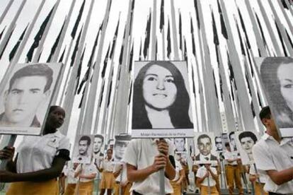 Estudiantes con fotografías de víctimas de Bahía de Cochinos en el <i>bosque </i>de banderas de La Habana.