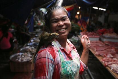 Una mujer camina con una especie de ardilla en su hombro, en el mercado de Maeklong, a las afueras de Bangkok (Tailandia).