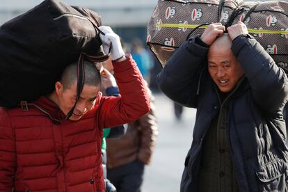 Viajeros transportan sus equipajes en la cabeza en la estación de tren de Pekín (China), el 1 de febrero de 2018.