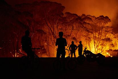 Unos vecinos observan las llamas en torno a su localidad,Tabourie Lake en Nueva Gales del Sur (Australia),  el 4 de enero.