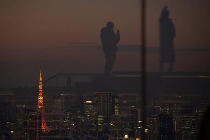 Reflejo de dos visitantes en las paredes de cristal de un mirador de un edificio de Tokio (Japón).