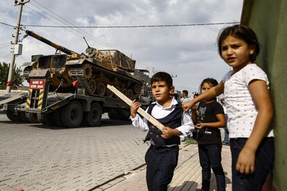 Los niños observan cómo los tanques del ejército son transportados en camiones a las afueras de la ciudad de Akcakale, sureste de Turquía.