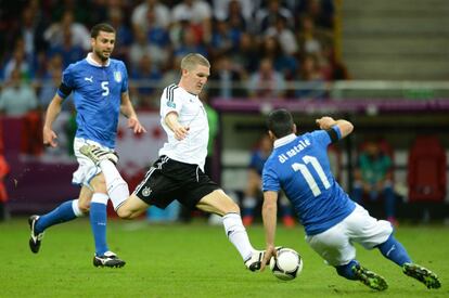 Bastian Schweinsteiger trata de lanzar, mientras Antonio Di Natale intenta cortarle el paso.