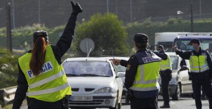 Varios agentes de Policía Nacional dan el alto a un vehículo en un control de movilidad en la parroquia de O Castiñeiriño (Santiago de Compostela), en la entrada y salida Santiago hacia Ourense (Galicia).