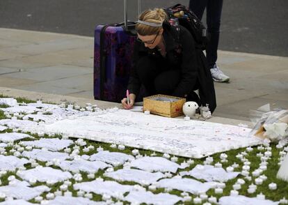 Cientos de personas hicieron anoche vigilia en la iglesia de Birstall, y también ante el Parlamento británico, en Londres. En la imagen, una mujer escribe unas palabras de condolencia tras el asesinato de la diputada Jo Cox, en Londres.