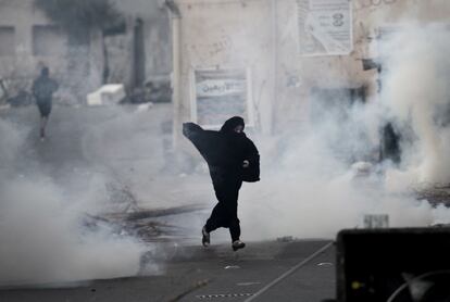 Una manifestante opositora al gobierno corre para protegerse del gas lacrimógeno lanzado por la policía antidisturbios durante los enfrentamientos tras una manifestación contra el gobierno en el pueblo de Daih, al oeste de Manama.