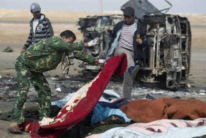 Rebeldes libios tapan los restos calcinados de soldados de Gadafi, muertos en el ataque aéreo aliado de ayer en Ajdabiya.