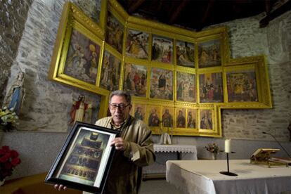 Aureliano Martínez, párroco de Horcajo de la Sierra, sujeta una imagen del retablo. Tras él, la copia expuesta en su Iglesia.