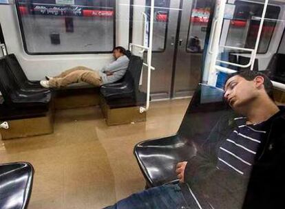 Dos jóvenes duermen en los vagones del metro de Barcelona a primeras horas de la mañana.