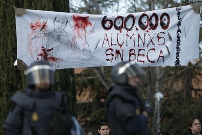 Miembros de los antidisturbios ante una pancarta en protesta por la cantidad de alumnos que se han quedado sin beca debido a la 'ley Wert'