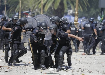 Os policiais auxiliam um colega ferido durante os distúrbios nas proximidades do Congresso. Os líderes sindicais se queixam de que a legislação, que já foi aprovada no Senado, cortaria os pagamentos de aposentadorias, bem como a ajuda para algumas famílias pobres.