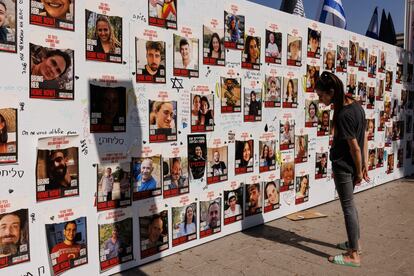 Una mujer observa una pared cubierta con las personas que aun se encuentran secuestradas en Gaza, este jueves en Tel Aviv, Israel. 
