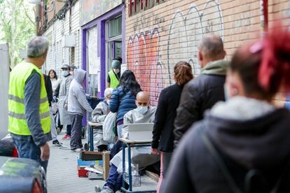 Un grupo de personas sin recursos hacen cola en Aluche, Madrid, para recibir alimentos.