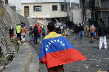 Um participante dos protestos envolto em uma bandeira nacional venezuelana.