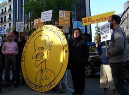 Los manifestantes de En Moviment, con una moneda con la caricatura de Camps, durante la protesta ante la sede del PP en la calle Génova de Madrid.