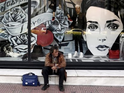 Un hombre sentado frente a una tienda en Atenas
