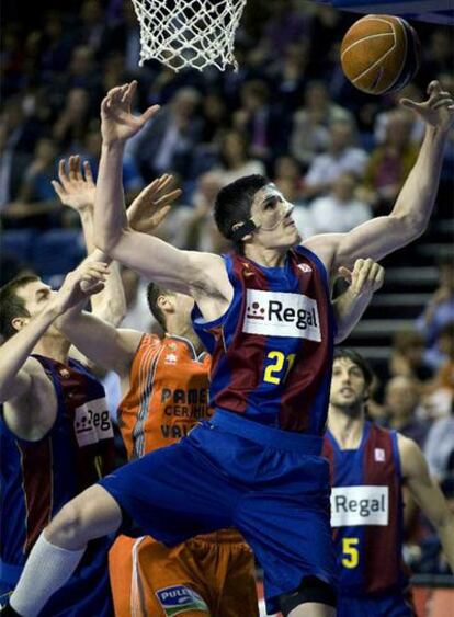 El ala-pívot turco del Regal Barcelona, Ersan Ilyasova (derecha), lucha por el rebote junto a su compañero, el pívot Fran Vázquez (izquierda), ante el pívot croata del Pamesa Valencia, Kosta Perovic.