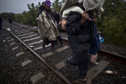 FILE - In this Friday, Sept. 11, 2015 file photo, Bara'ah Alhammadi, 10, a Syrian migrant, is carried on the back of her father as they make their way along a railway track after crossing the Serbian-Hungarian border near Roszke, southern Hungary. The U.N. agency for children says more than 80 percent of Syria's children have been harmed by the five-year-old conflict, including growing numbers forced to work, join armed groups or marry young because of widening poverty. (AP Photo/Muhammed Muheisen, File)