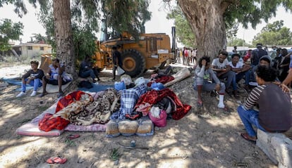 Varios migrantes permanecen en el exterior del centro de detención de Tayura después del bombardeo.