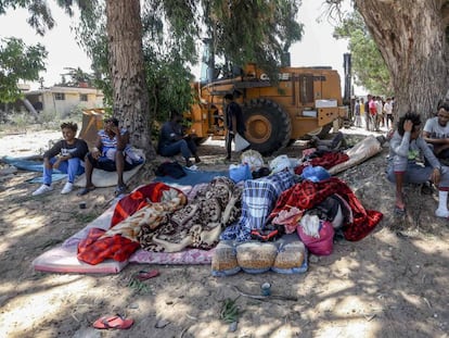 Varios migrantes permanecen en el exterior del centro de detención de Tayura después del bombardeo.