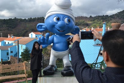 Turistas fotografiándose con la estatua de un pitufo