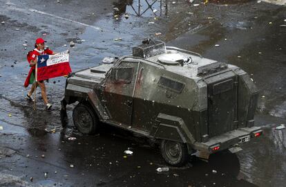 Una manifestante sostiene una bandera chilena frente a un vehículo blindado de la policía durante una marcha antigubernamental en Santiago de Chile.