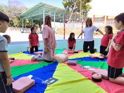 Dos facultativas enseñan a varios niños cómo hacer una recuperación cardiopulmonar.