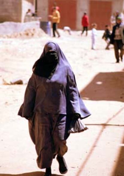 En la página de la izquierda, una mujer con su cuerpo totalmente cubierto, en el barrio Ued Dahab (de Salé).