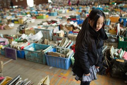 Una niña japonesa pasea entre los libros y pertenencias recuperadas de las ruinas.